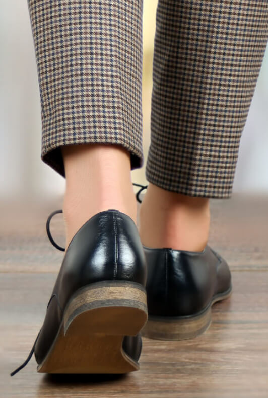 Donna con scarpe per l'ufficio stringate nere e pantaloni a quadretti